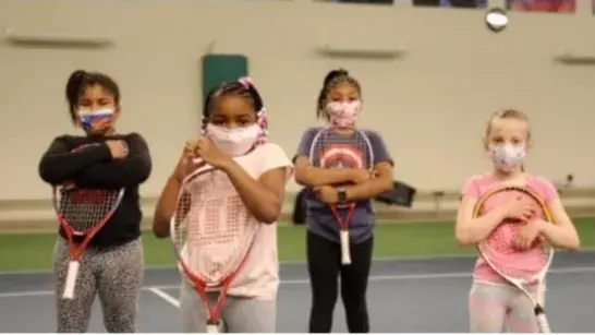 Four young girls holding tennis rackets