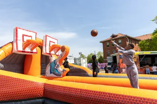 A kid attempting to score a basket in a bouncy basketball court setup