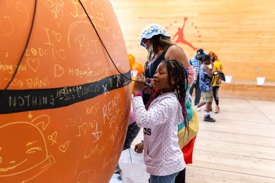 A kid adding to the craft already present on a huge basketball