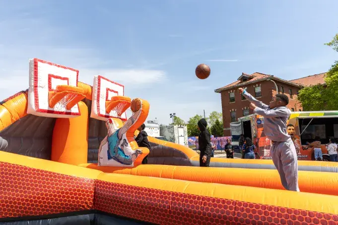 A kid attempting to score a basket in a bouncy basketball court setup